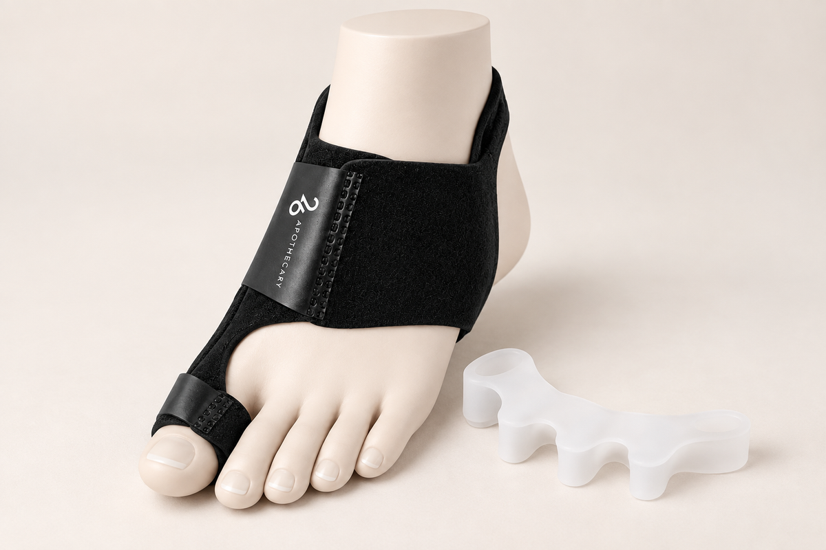 A black toe spacer brace shown on a mannequin foot, with a translucent white silicone toe spacer placed beside it on a light beige background.